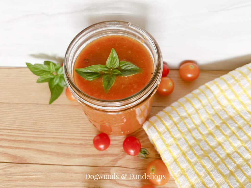 roasted cherry tomato sauce with a sprig of basil surrounded by cherry tomatoes and a towel