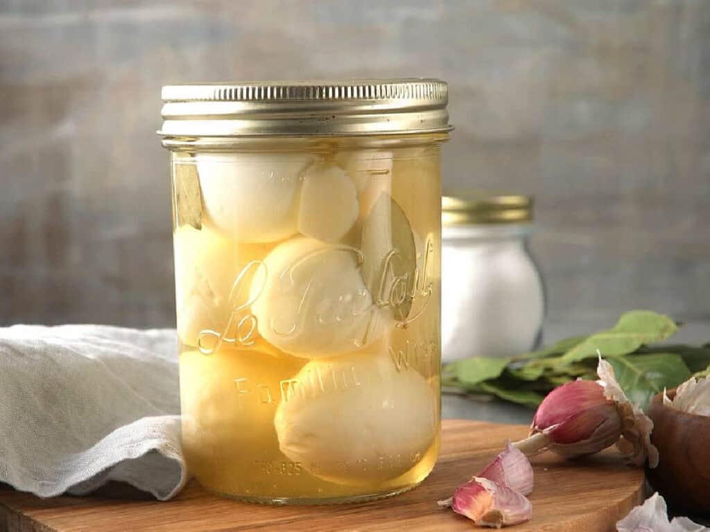 pickled hardboiled eggs in a jar with salt and garlic on the side
