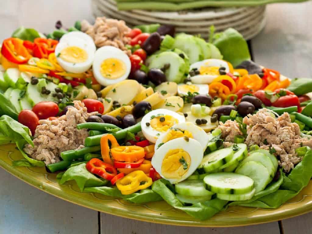 a salmon salad with cucumbers, hardboiled eggs, and green beans