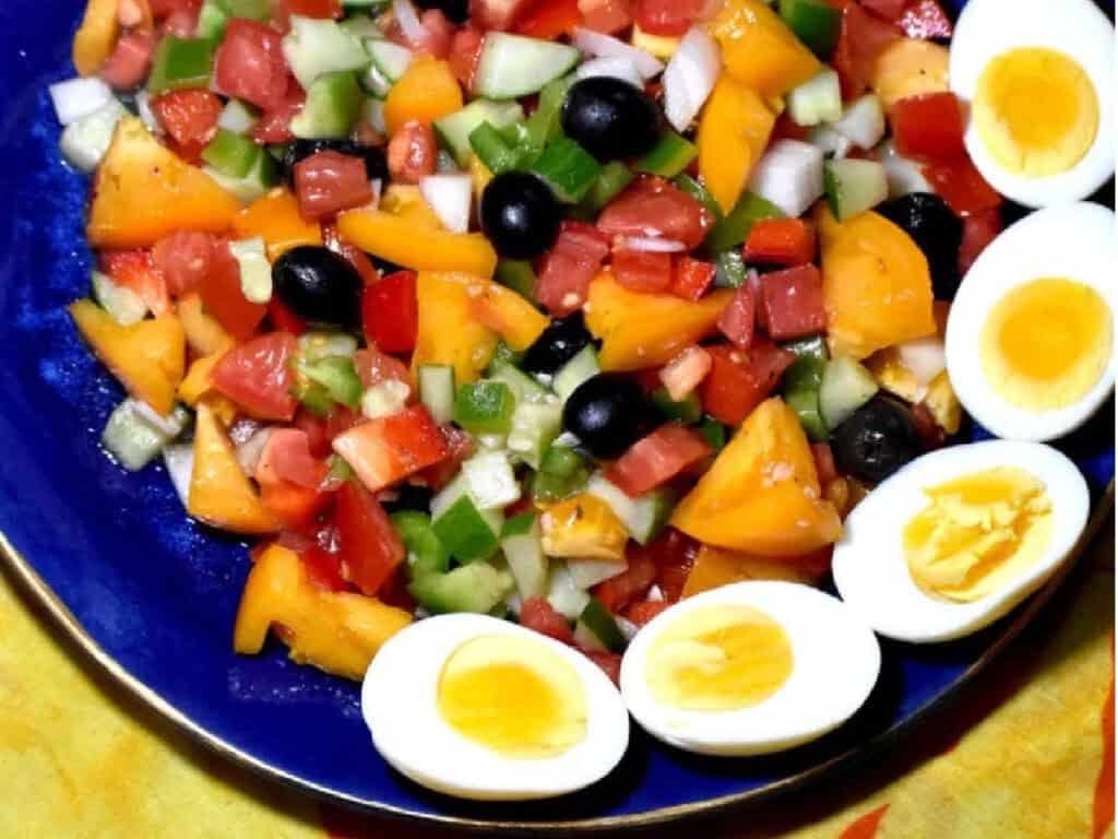 a spanish salad with hardboiled eggs, olives, peppers, and cucumbers