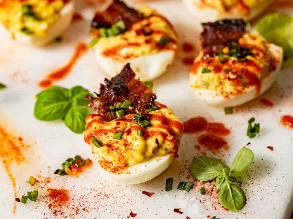 spicy deviled eggs with bacon and basil on the side