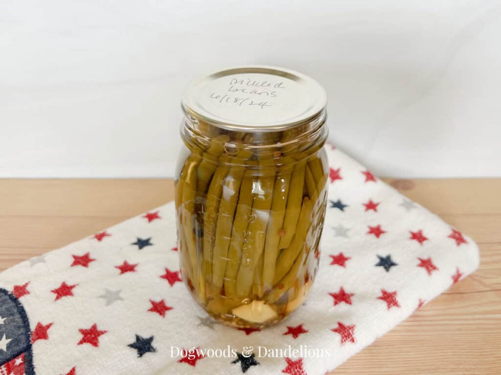 a jar of pickled green beans sitting on a towel with red and blue stars