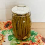 a jar of pickled green beans sitting on a sunflower towel