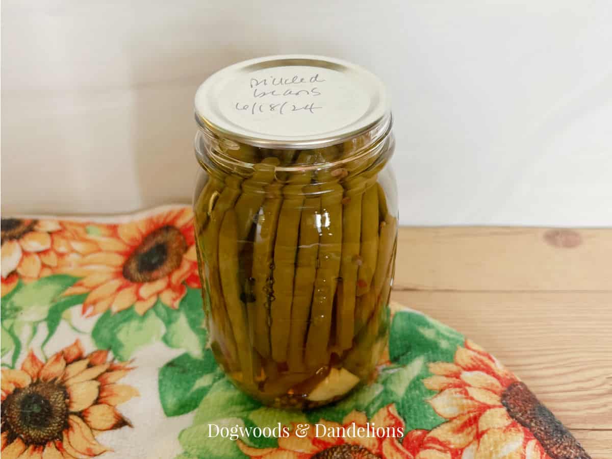a jar of pickled green beans sitting on a sunflower towel
